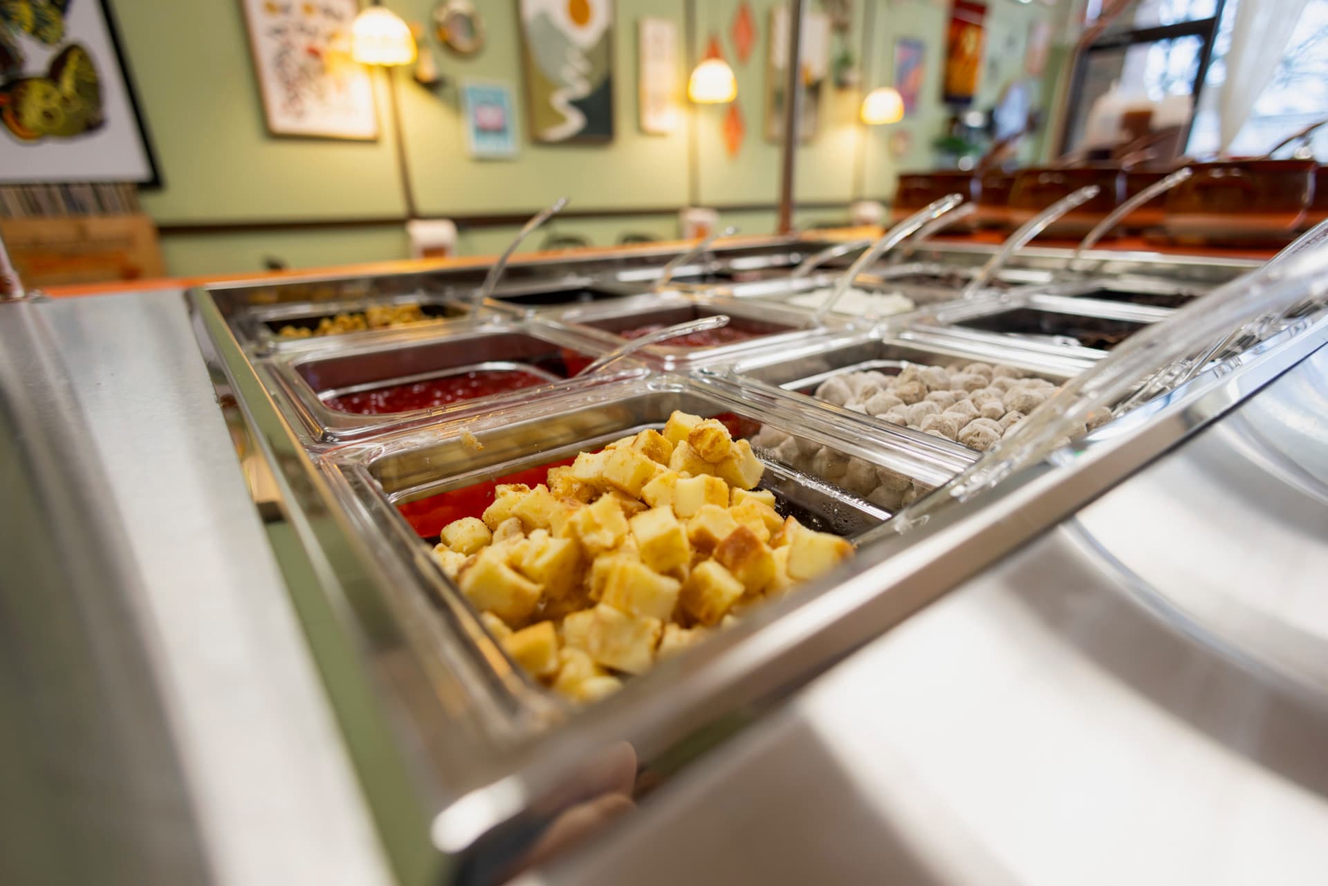 A close-up view of a colorful salad bar featuring various toppings in clear containers.