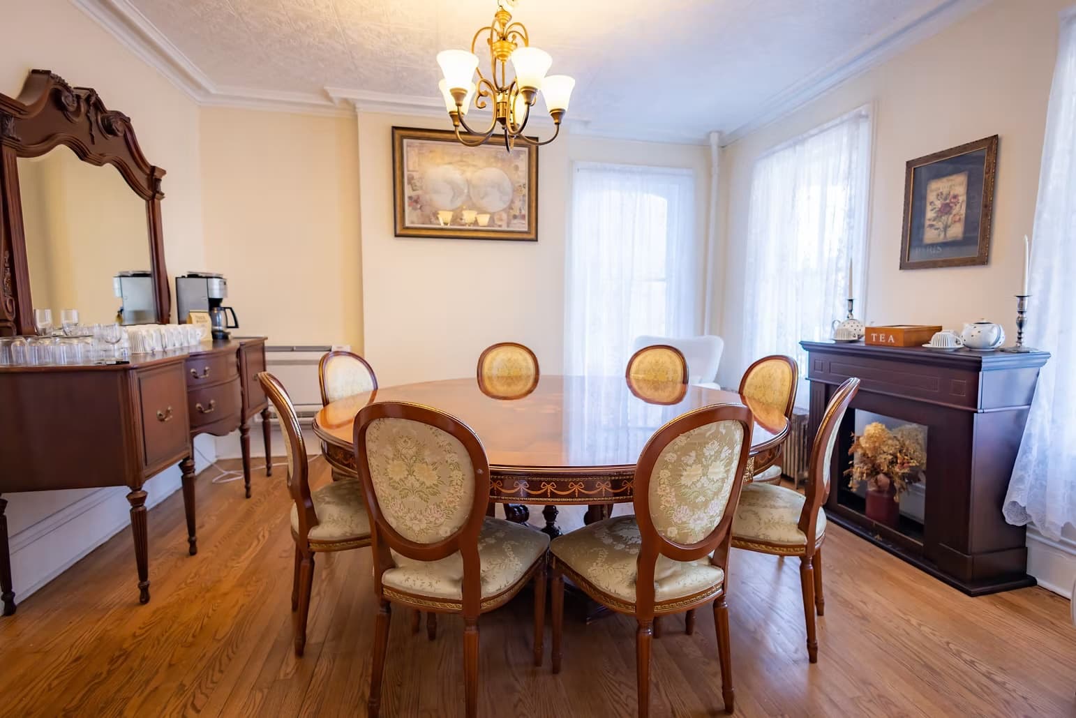 A well-furnished dining room featuring a round table surrounded by ornate chairs and a chandelier overhead.